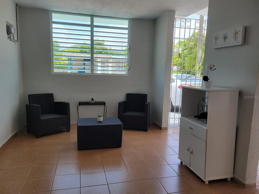 A covered patio features tiled flooring, two dark wicker chairs, a matching table, and a cabinet — B4 ST GUATEMALA UNIT B4, HUMACAO, PR