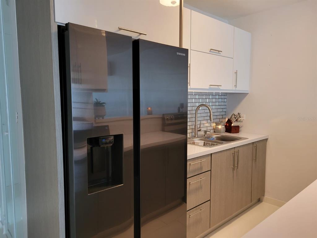 A kitchen features a black refrigerator, light wood cabinets, white upper cabinets, and a tiled backsplash — B4 ST GUATEMALA UNIT B4, HUMACAO, PR