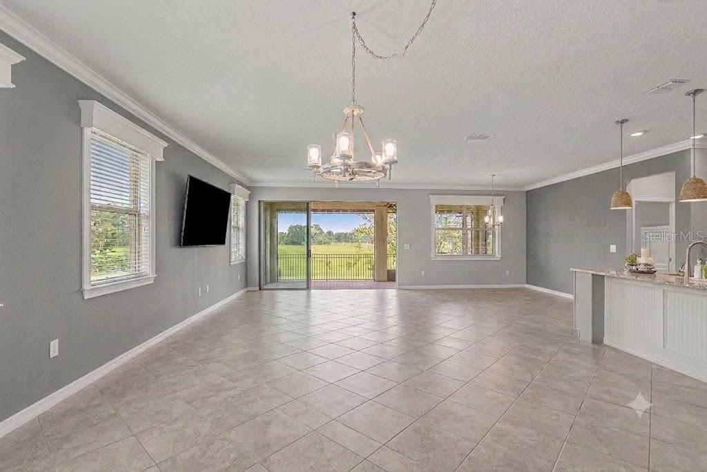 An open-concept living and dining area features tile flooring, a chandelier, and sliding glass doors — 9793 SW 63RD LOOP, OCALA, FL