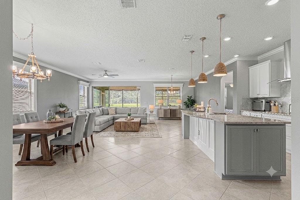 An open-concept kitchen, dining area, and living room with tile floors and neutral gray walls — 9793 SW 63RD LOOP, OCALA, FL