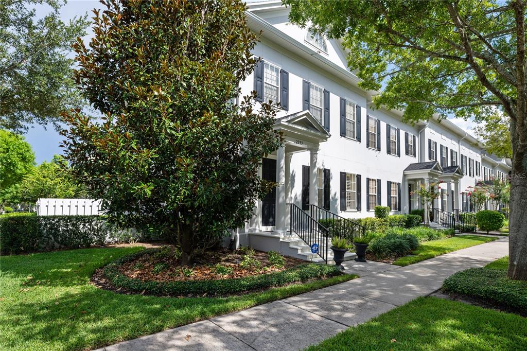 A white multi-story townhouse exterior features black shutters, a front porch, and a landscaped yard — 2293 OSPREY AVENUE, ORLANDO, FL
