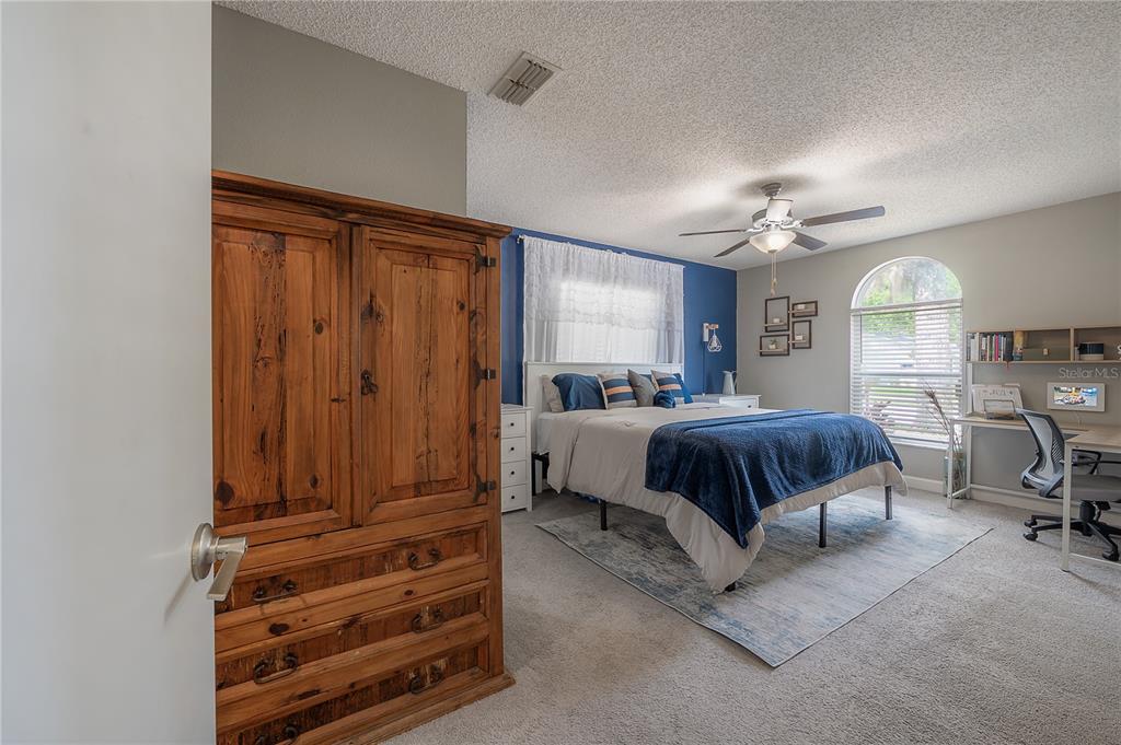 A bedroom features a wooden armoire, a bed with blue bedding, and a corner desk — 13210 WHALER DRIVE, HUDSON, FL