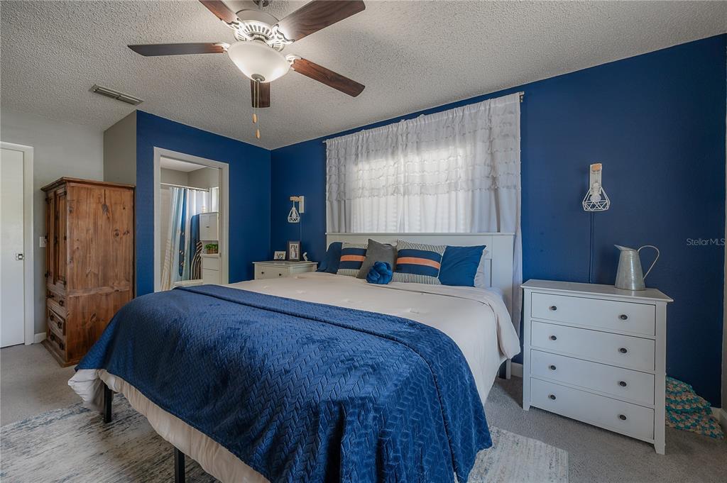 A bedroom features blue walls, a white bed with a blue quilt, and white dressers — 13210 WHALER DRIVE, HUDSON, FL