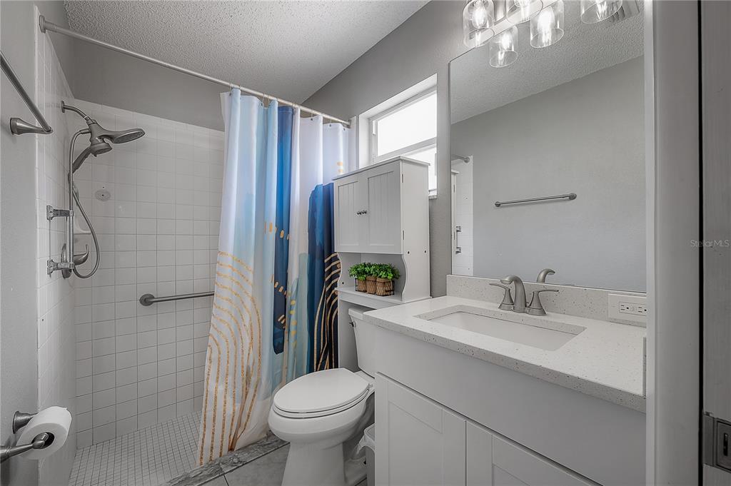 A bathroom features a white vanity, a toilet, and a shower with a patterned curtain — 13210 WHALER DRIVE, HUDSON, FL