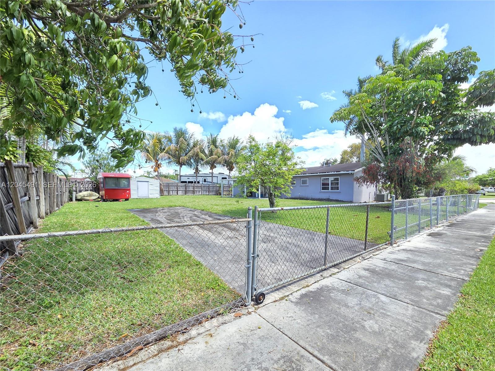 A fenced yard features a paved driveway, a small shed, and a single-story house — 12061 SW 119th St, Miami FL 33186, MIAMI, FL