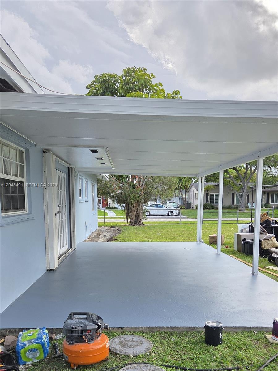 A covered concrete patio extends from the side of a light blue house — 12061 SW 119th St, Miami FL 33186, MIAMI, FL