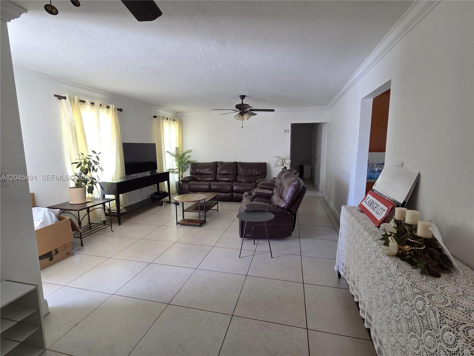 A living room features light tile flooring, a brown leather sofa, and a ceiling fan — 12061 SW 119th St, Miami FL 33186, MIAMI, FL