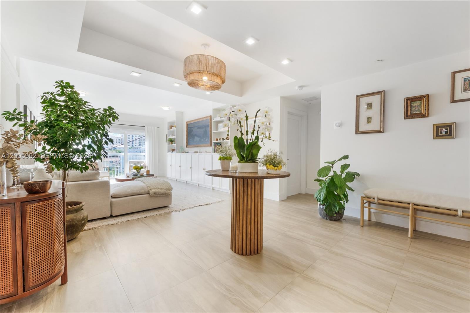 A bright, open-plan living area features light tile flooring, a central pedestal table, and plants — 120 Salamanca Ave # 3B, Coral Gables FL 33134, CORAL GABLES, FL
