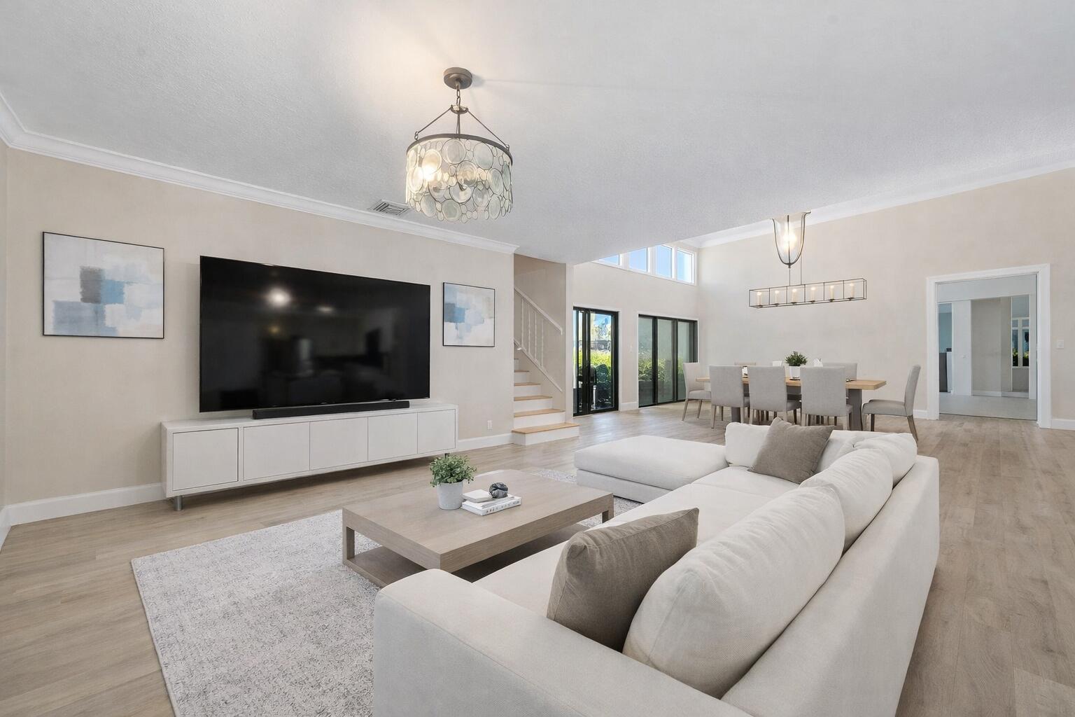 A bright, open-concept living and dining area features light wood floors and neutral furniture — 3000 Conifer Drive, Fort Pierce FL 34951, FORT PIERCE, FL
