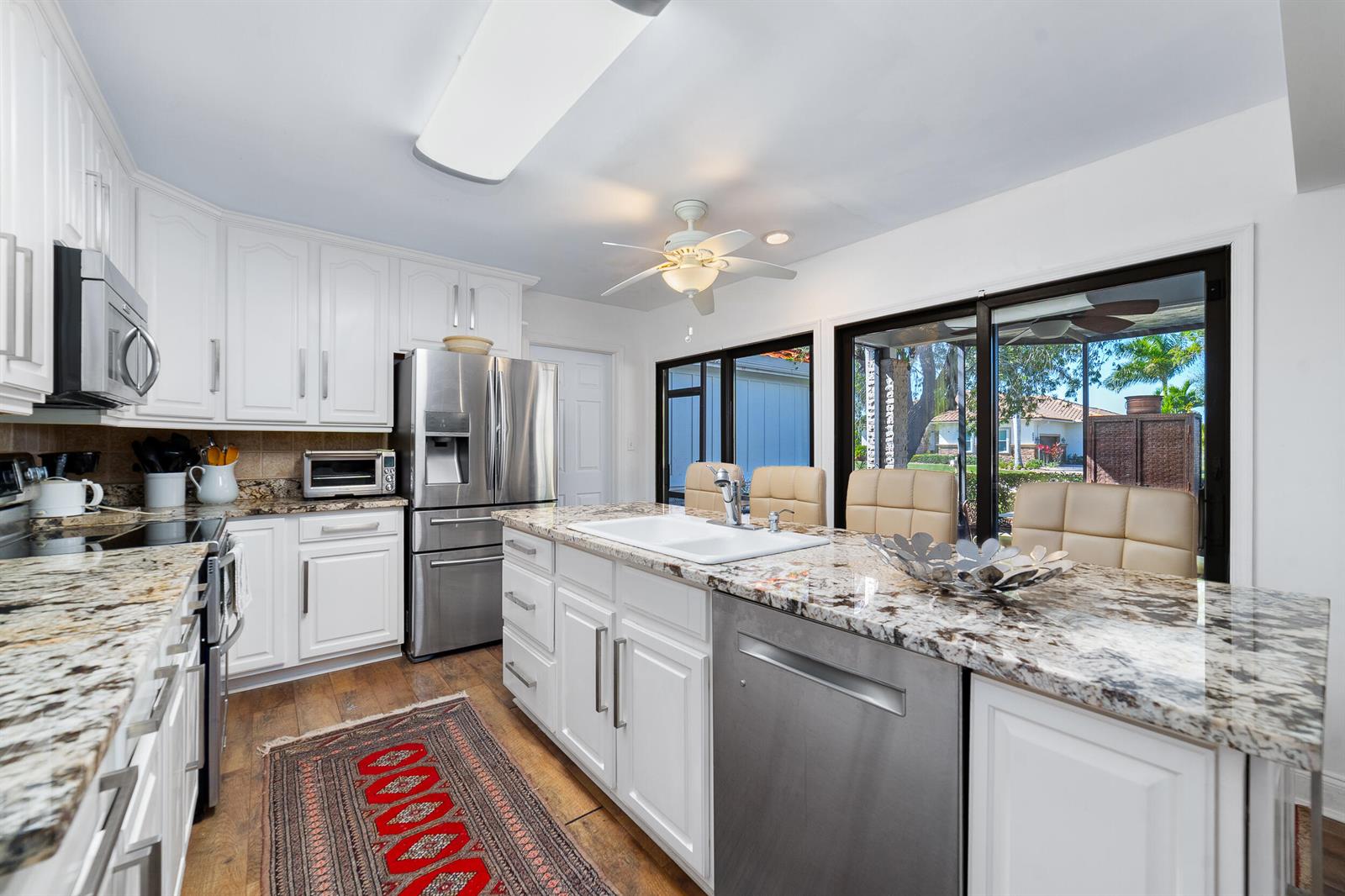 A kitchen features white cabinetry, granite countertops, stainless steel appliances, and a central island — 3000 Conifer Drive, Fort Pierce FL 34951, FORT PIERCE, FL