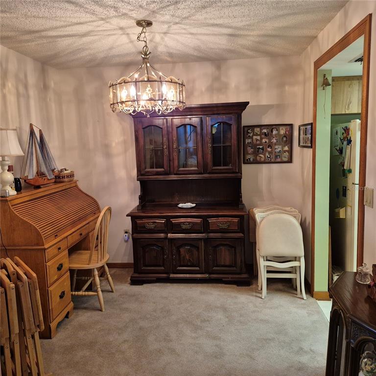 A dining room features a wooden hutch, a roll-top desk, and a decorative chandelier — 7828 ROYAL STEWART DRIVE, NEW PORT RICHEY, FL