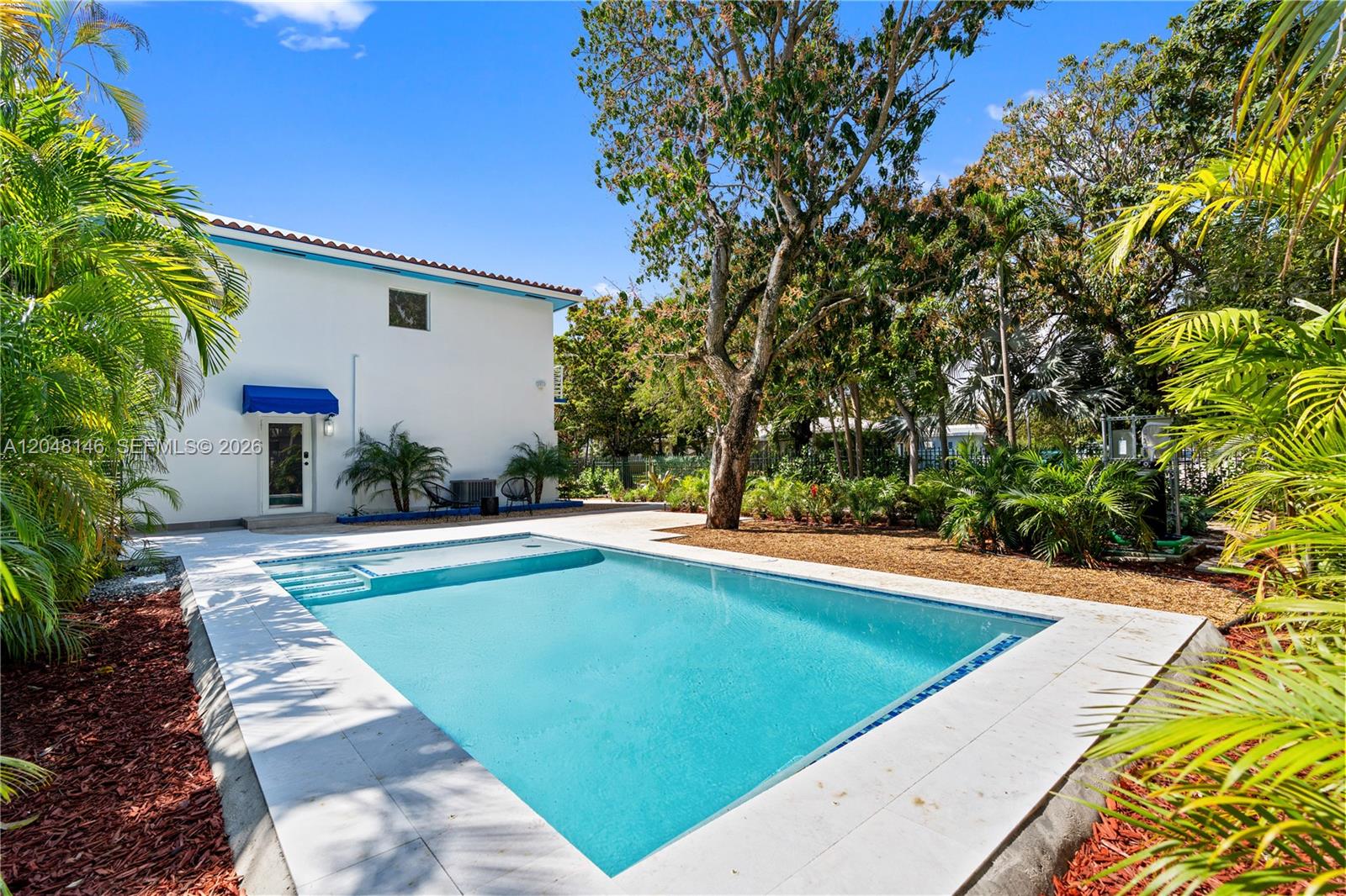 A rectangular swimming pool sits in a backyard next to a white two-story house — 1345 SW 14th Ave, Miami FL 33145, MIAMI, FL