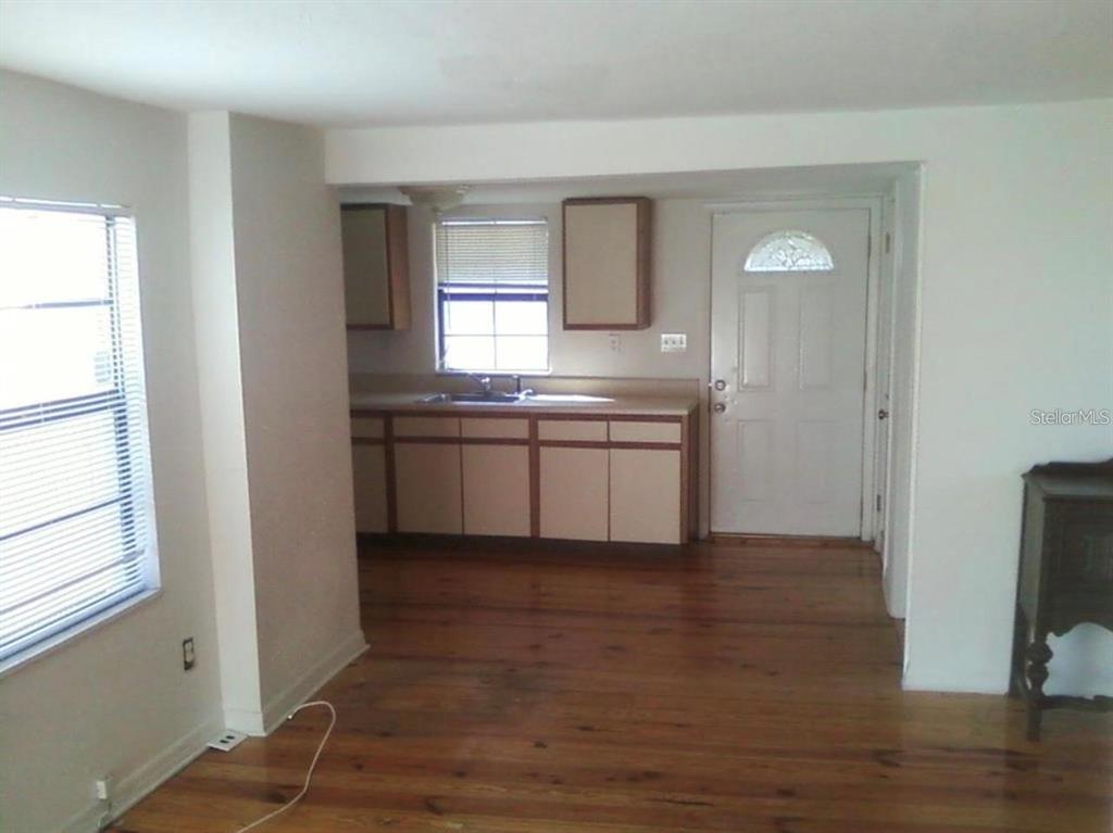 An interior view shows a kitchen with light-colored cabinets and wood flooring — 7205 S MANHATTAN AVENUE, TAMPA, FL