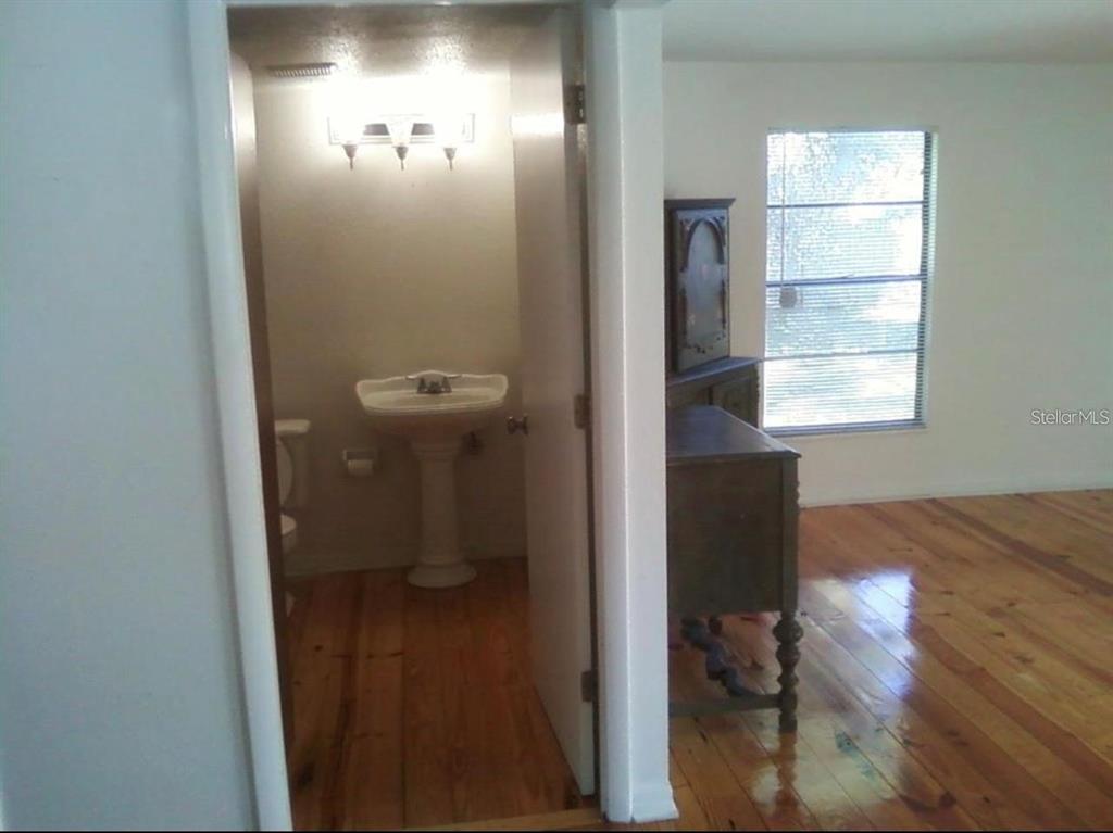 A bathroom with a pedestal sink is visible through an open doorway next to a room — 7205 S MANHATTAN AVENUE, TAMPA, FL