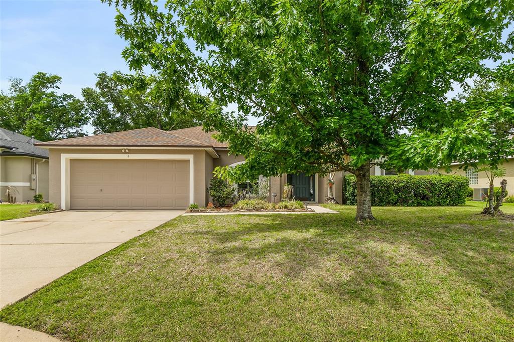 A single-story house with a tan exterior, a two-car garage, and a large front tree — 6 EVANSVILLE LANE, PALM COAST, FL