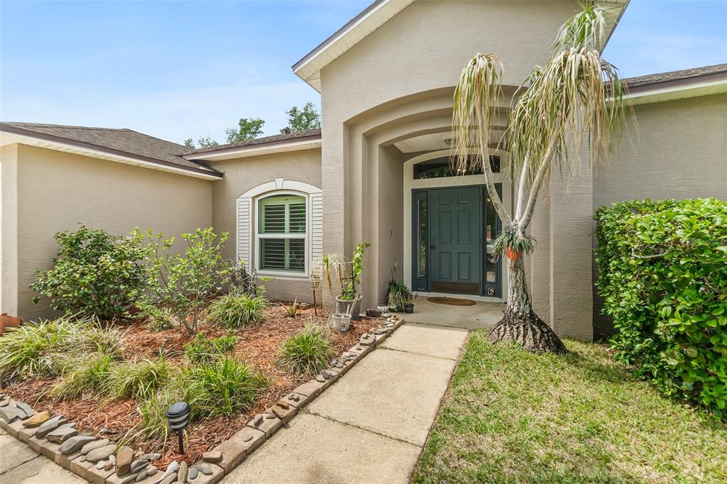The exterior of a beige house features a dark blue front door and a palm tree — 6 EVANSVILLE LANE, PALM COAST, FL