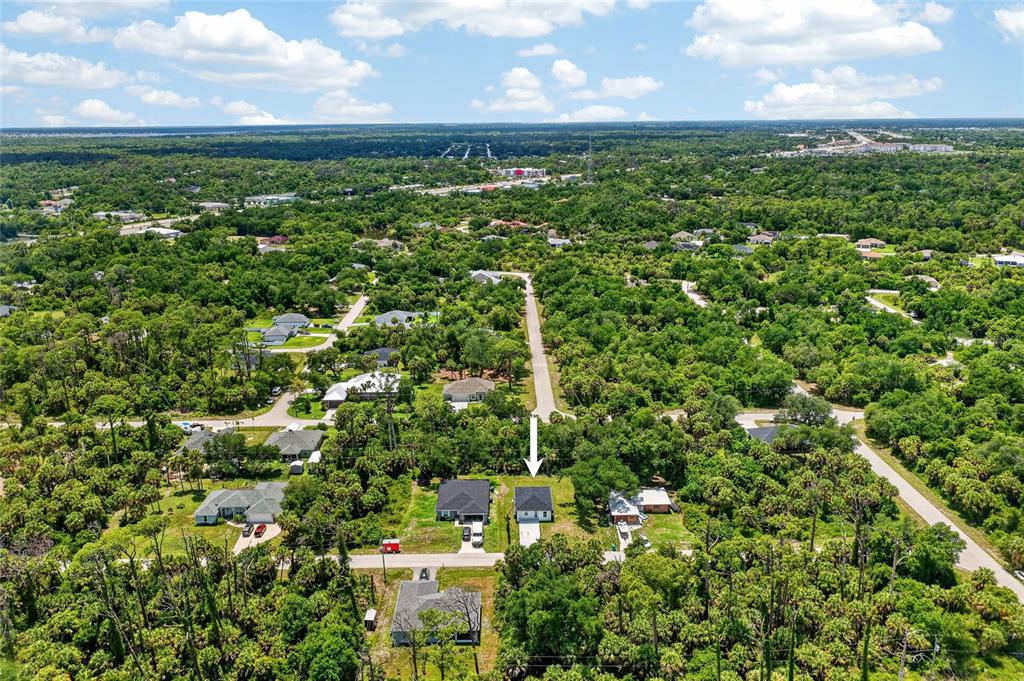 An aerial view shows a single-family home surrounded by dense trees and neighborhood roads — 369 AVELLA STREET, PORT CHARLOTTE, FL