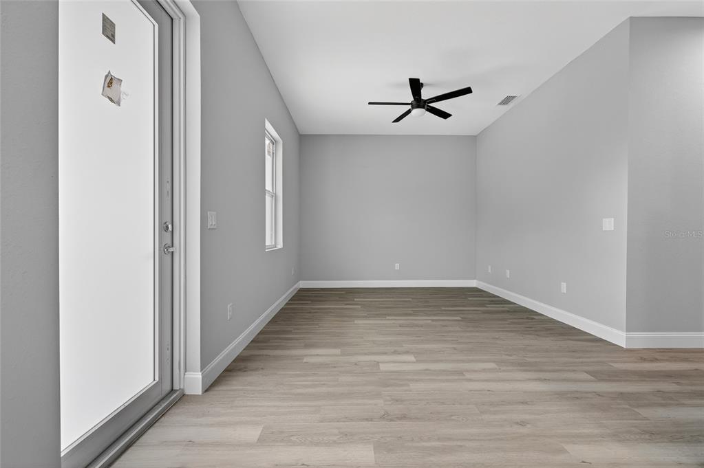 An empty room with light gray walls, wood-look flooring, a ceiling fan, and a glass door — 369 AVELLA STREET, PORT CHARLOTTE, FL