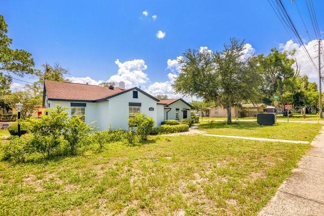 A light-colored house with a brown roof sits on a grassy lot with trees — 604 N SINCLAIR AVENUE, TAVARES, FL