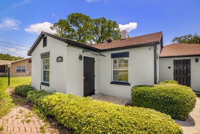 A white house with a dark door and a manicured hedge in the front yard — 604 N SINCLAIR AVENUE, TAVARES, FL