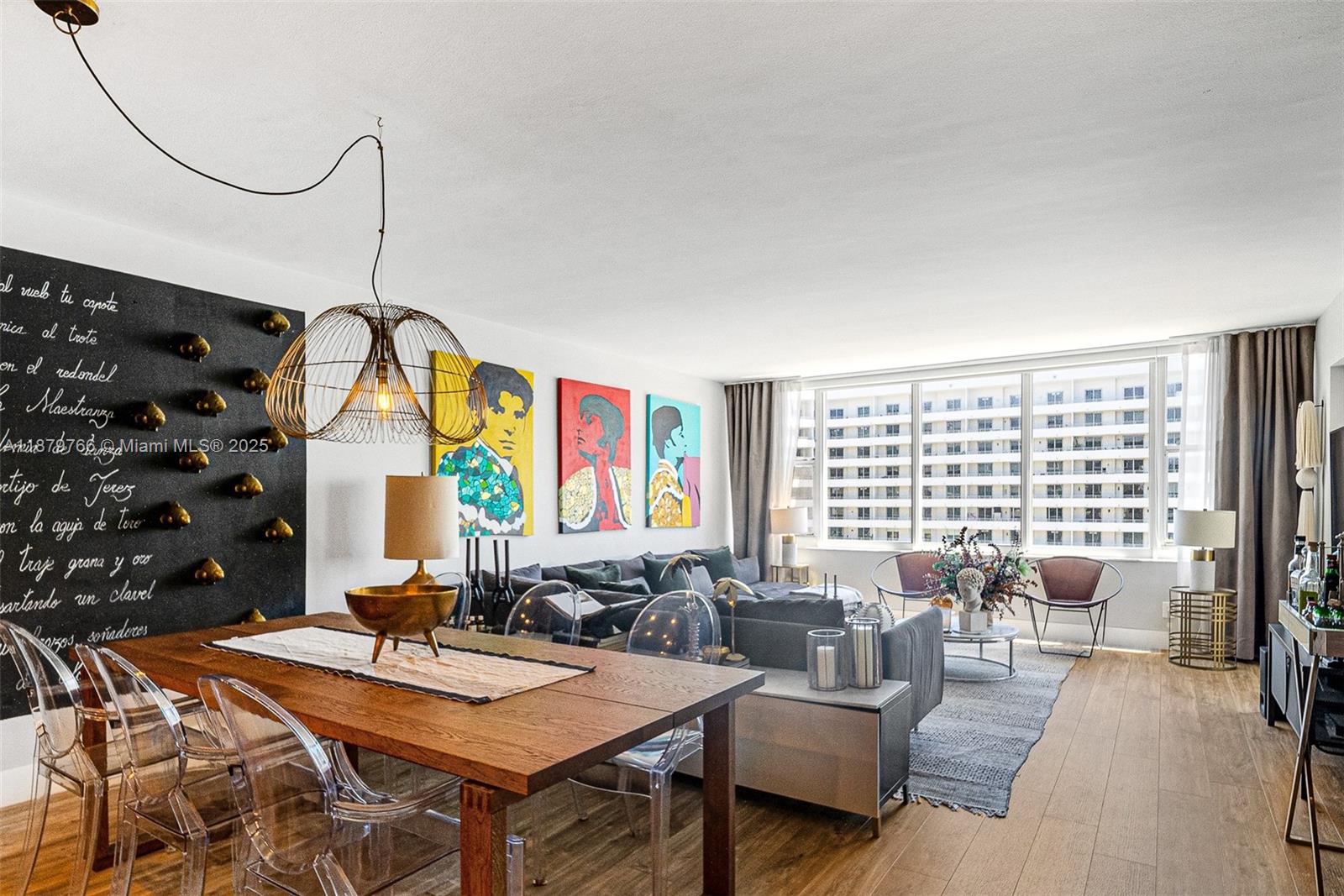 A living and dining area features a chalkboard wall, colorful artwork, and floor-to-ceiling windows — 5600 Collins Ave # 12E, Miami Beach FL 33140, MIAMI BEACH, FL
