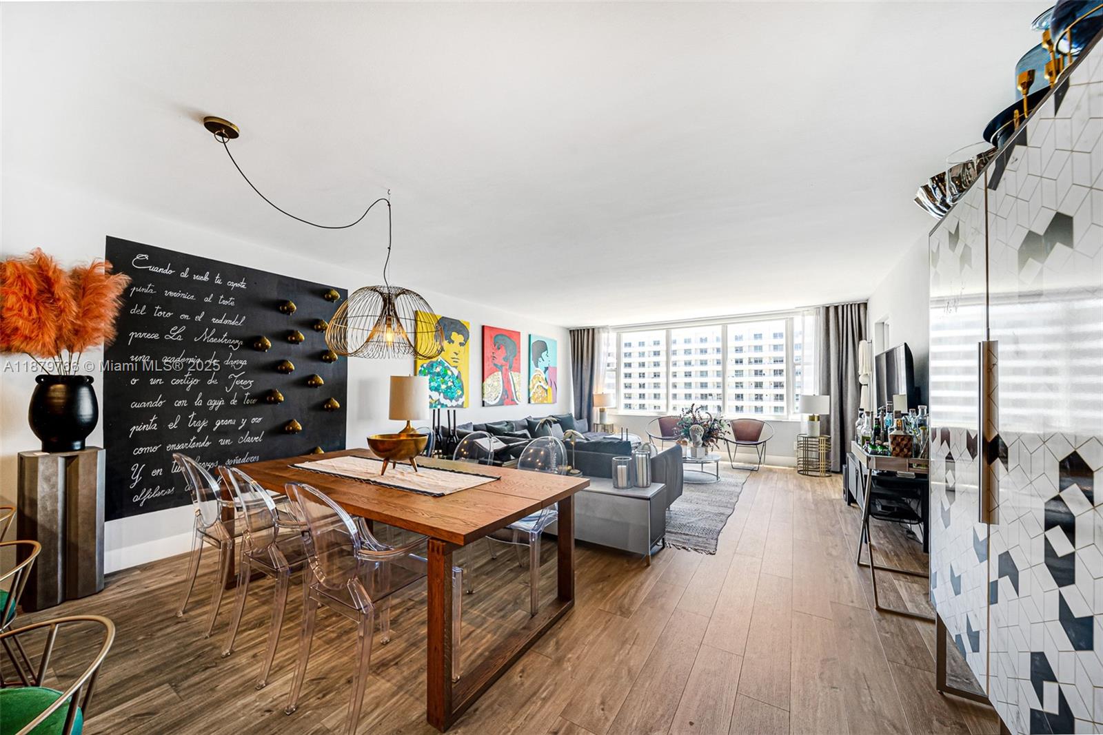 A dining and living area features a wooden table, transparent chairs, and a chalkboard wall — 5600 Collins Ave # 12E, Miami Beach FL 33140, MIAMI BEACH, FL