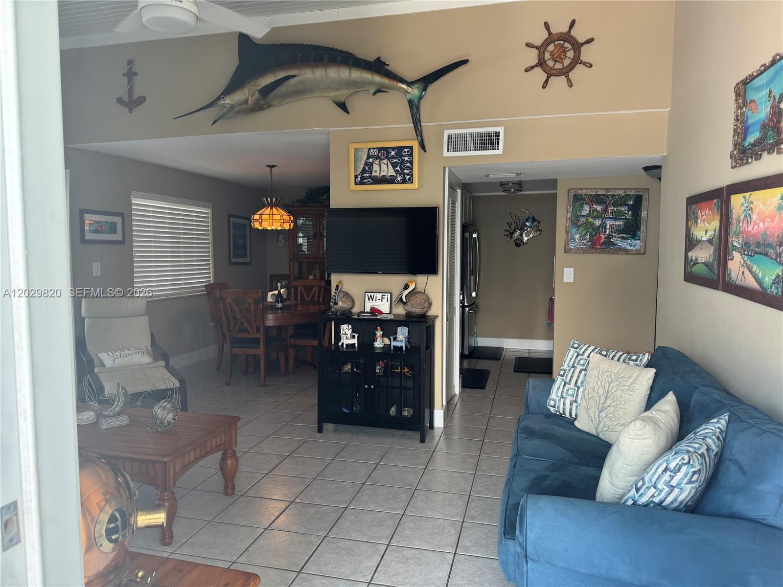 A living and dining area features tile flooring, a blue sofa, and nautical wall decor — 118 Cortez Dr # B, Islamorada FL 33036, ISLAMORADA, FL
