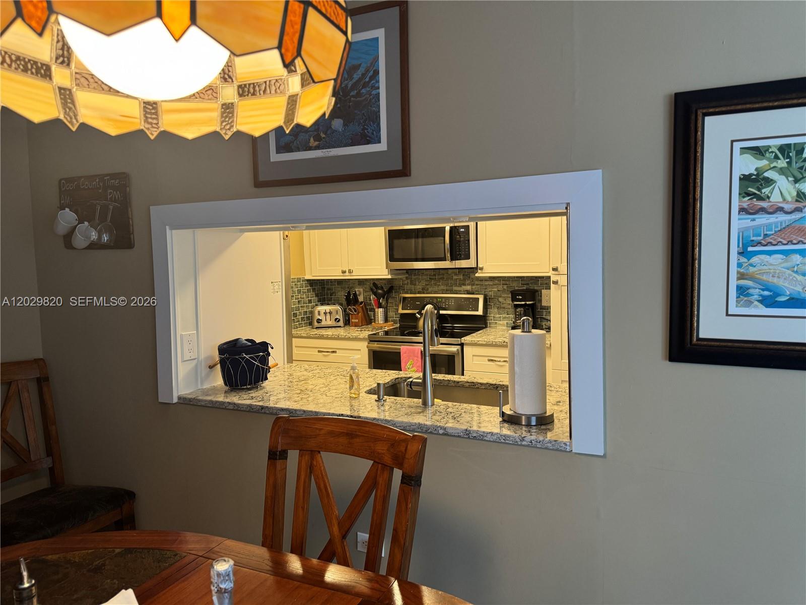A kitchen pass-through window with granite countertops overlooks a dining area — 118 Cortez Dr # B, Islamorada FL 33036, ISLAMORADA, FL