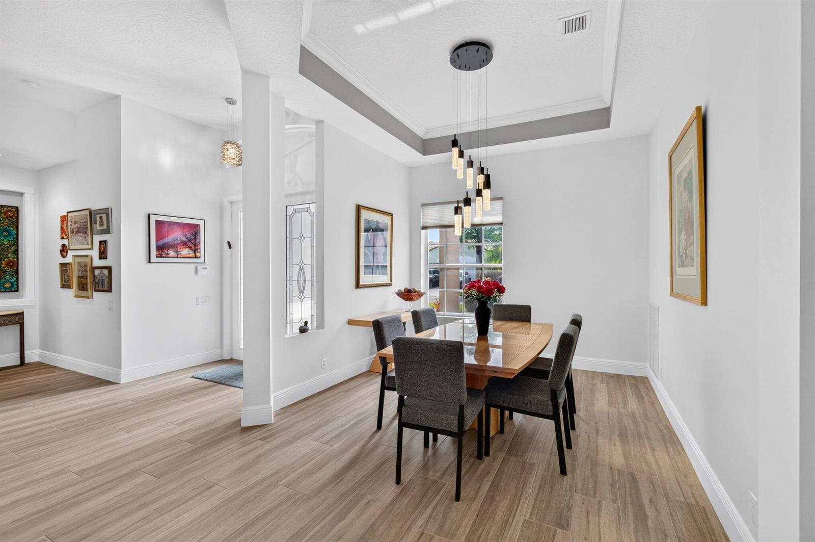 A dining room with a glass table, grey chairs, and a modern tiered pendant light — 8969 Torcello Way, Boynton Beach FL 33472, BOYNTON BEACH, FL