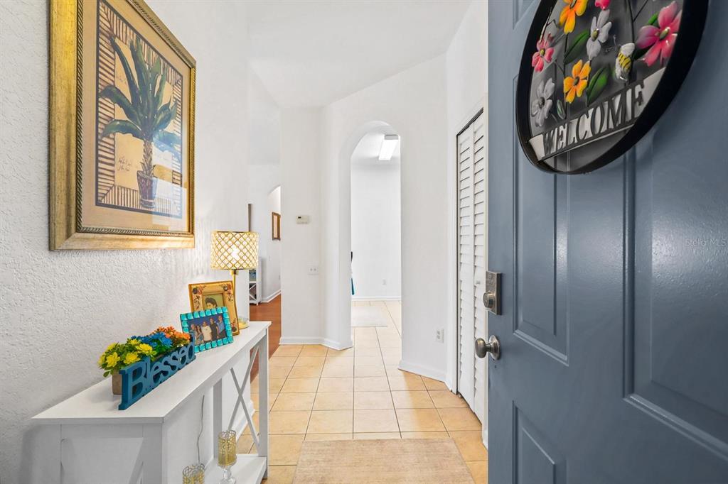 An entryway features a white console table, a framed palm tree print, and a blue door — 2310 SILVER PALM DRIVE UNIT 201, KISSIMMEE, FL