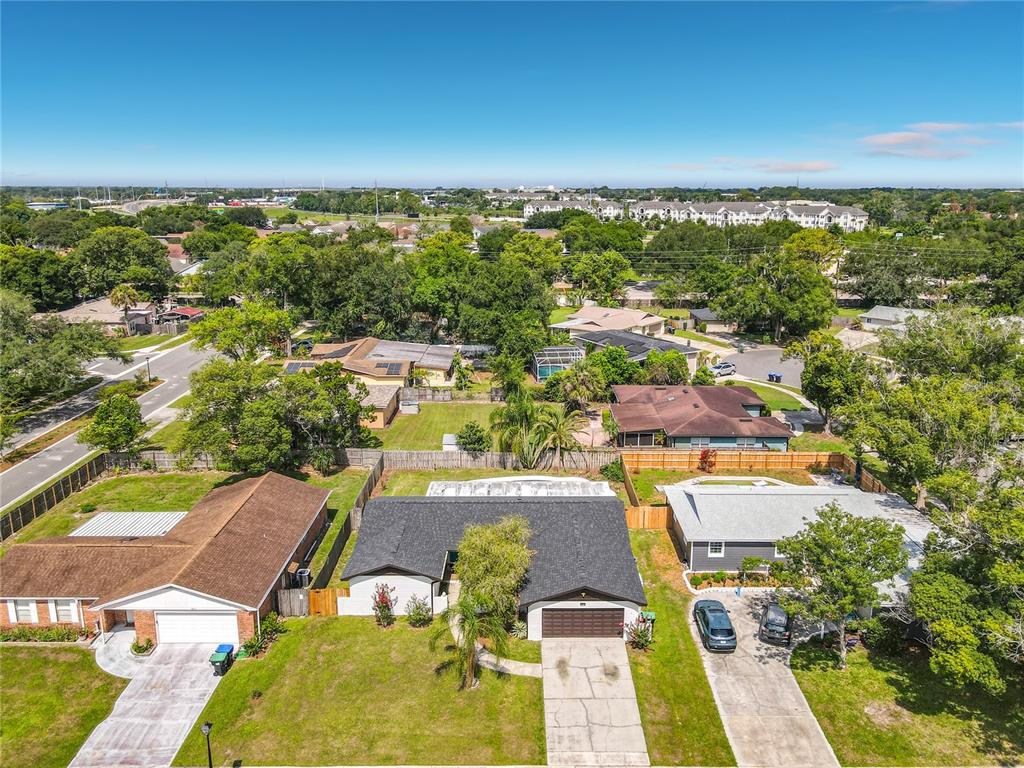 An aerial view shows three suburban houses with driveways and lawns in a residential neighborhood — 8676 HILLSIDE DRIVE, ORLANDO, FL