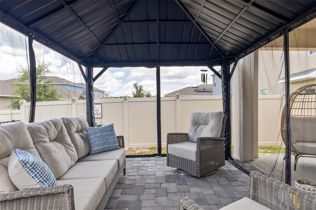 A covered patio features a metal gazebo, wicker furniture, and a paved stone floor — 1452 CUMBERLAND AVENUE, DAVENPORT, FL