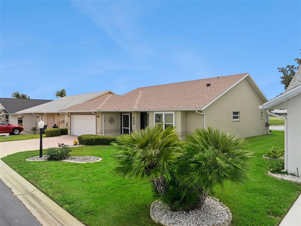 A single-story house with a tan stucco exterior, a shingled roof, and a front lawn — 501 EASTLAKE DRIVE, HAINES CITY, FL