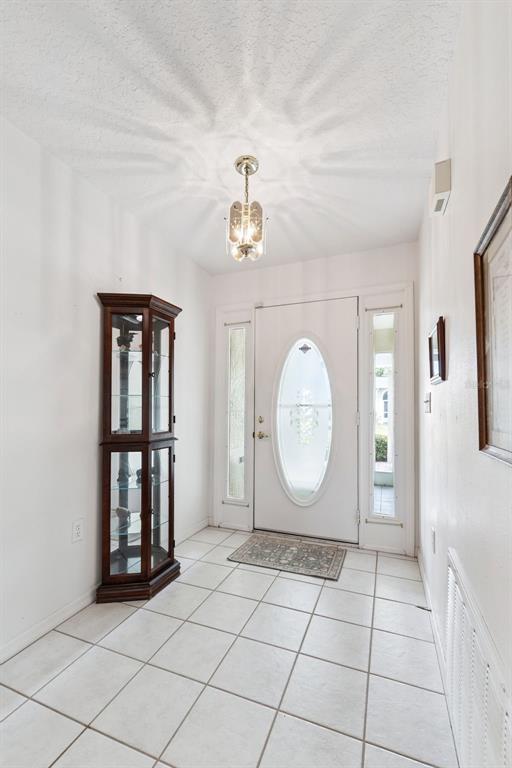 A tiled entryway features a white front door with an oval glass insert and a curio — 501 EASTLAKE DRIVE, HAINES CITY, FL