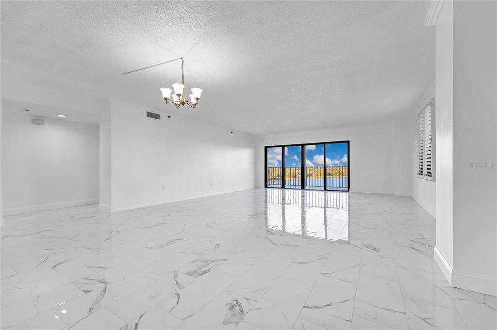 An open-concept living room features white marble-look tile flooring and a sliding glass door — 7550 HINSON STREET UNIT 10A, ORLANDO, FL