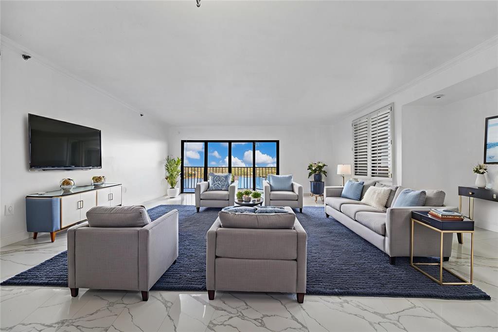 A bright living room features white marble floors, a large blue rug, and balcony views — 7550 HINSON STREET UNIT 10A, ORLANDO, FL