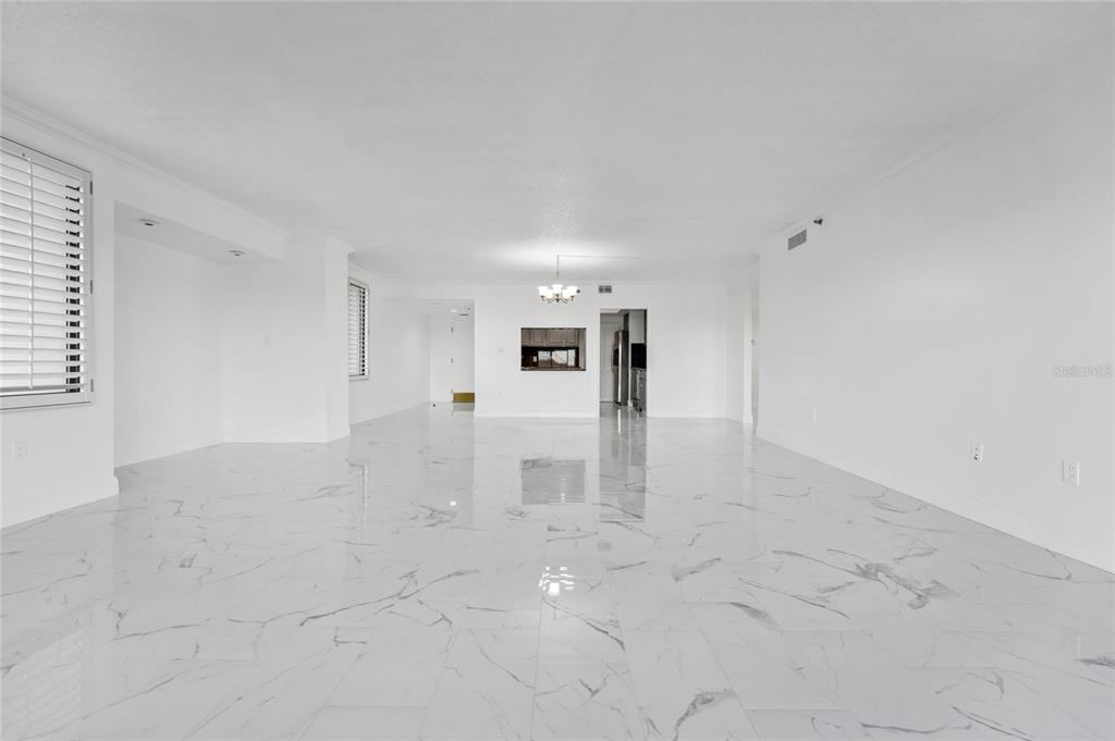 A spacious, empty room features white walls, a white marble-look tiled floor, and a chandelier — 7550 HINSON STREET UNIT 10A, ORLANDO, FL