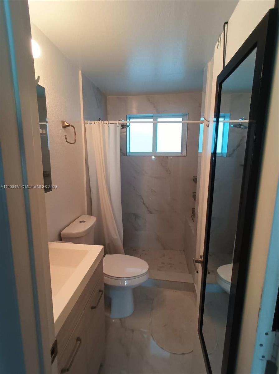 A bathroom features a vanity, a toilet, and a shower area with marble-look tile walls — 300 74th St # 3, Miami Beach FL 33141, MIAMI BEACH, FL