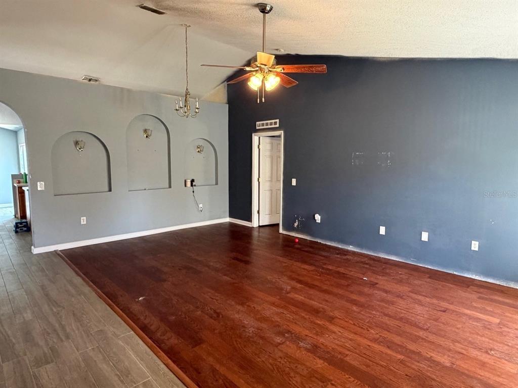 A living room features a dark accent wall, a ceiling fan, and mixed wood flooring — 135 VERVAIN AVENUE, DAVENPORT, FL