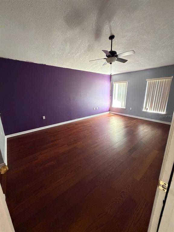 An empty room features dark wood flooring, a purple accent wall, and a ceiling fan — 135 VERVAIN AVENUE, DAVENPORT, FL
