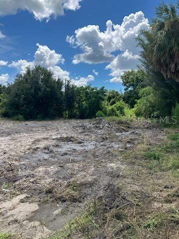 A vacant, cleared lot with patches of mud and surrounding trees under a cloudy sky — 2011 CALLE BONITO, PUNTA GORDA, FL