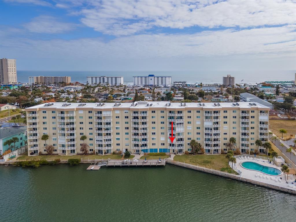 An aerial view shows a multi-story waterfront condominium building with a pool and dock — 3606 S PENINSULA DRIVE UNIT 208, PORT ORANGE, FL