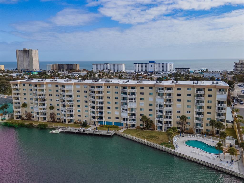 An aerial view shows a multi-story apartment building with a pool and a boat dock — 3606 S PENINSULA DRIVE UNIT 208, PORT ORANGE, FL