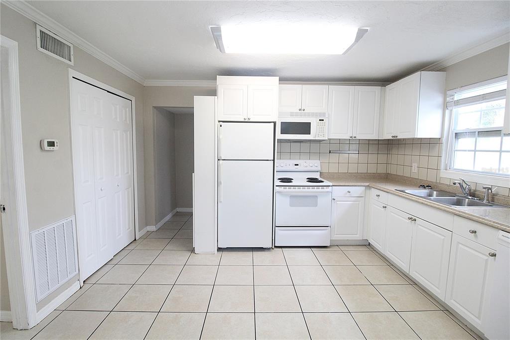 A kitchen with white cabinets, white appliances, tiled floors, and a window above the sink — 1638 REDWOOD STREET UNIT 1, SARASOTA, FL