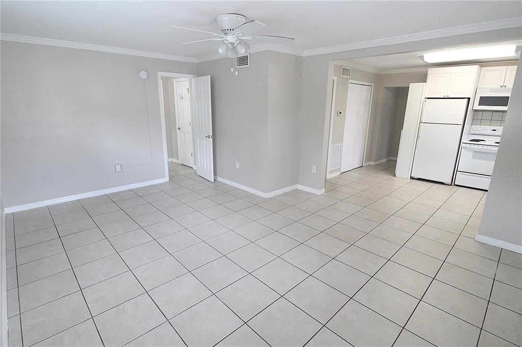 An open-concept living area with light-colored tile flooring, a ceiling fan, and an adjacent kitchen — 1638 REDWOOD STREET UNIT 1, SARASOTA, FL