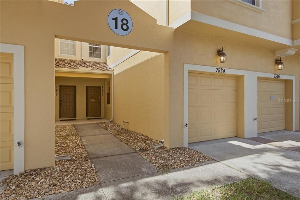 The exterior of a multi-unit residential building features two garage doors and two entry doors — 7524 BLISS WAY UNIT 7524, KISSIMMEE, FL