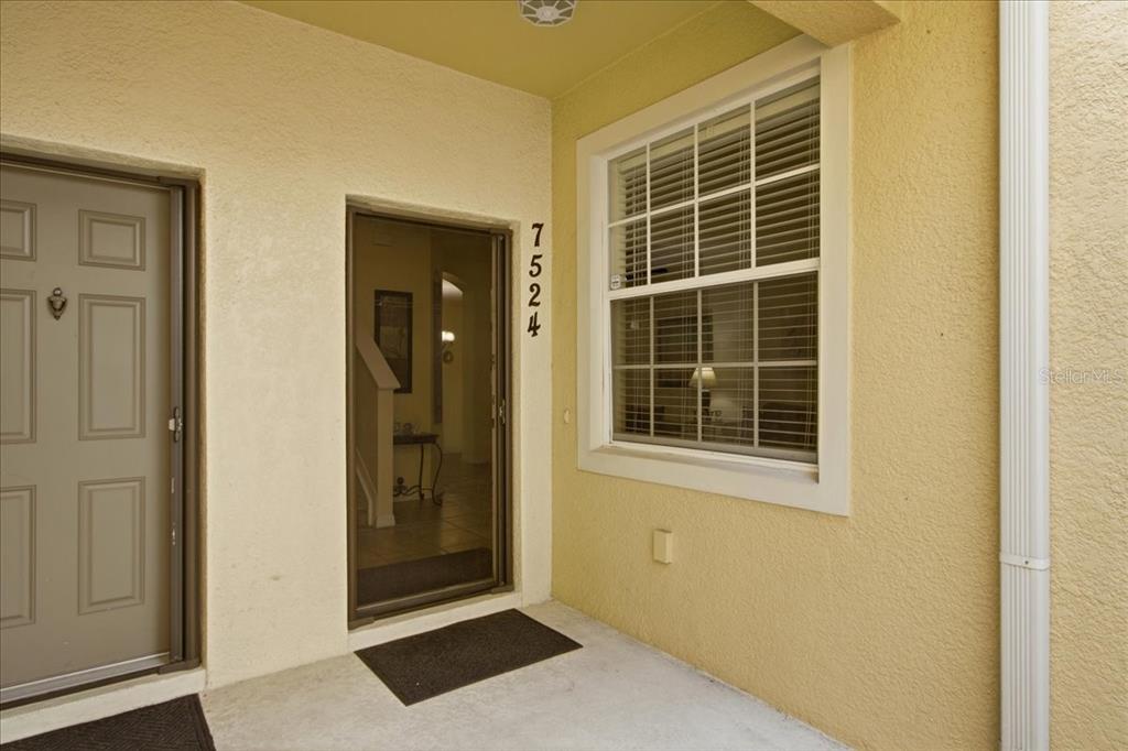 The exterior entryway features a tan stucco wall, a front door, and a window — 7524 BLISS WAY UNIT 7524, KISSIMMEE, FL