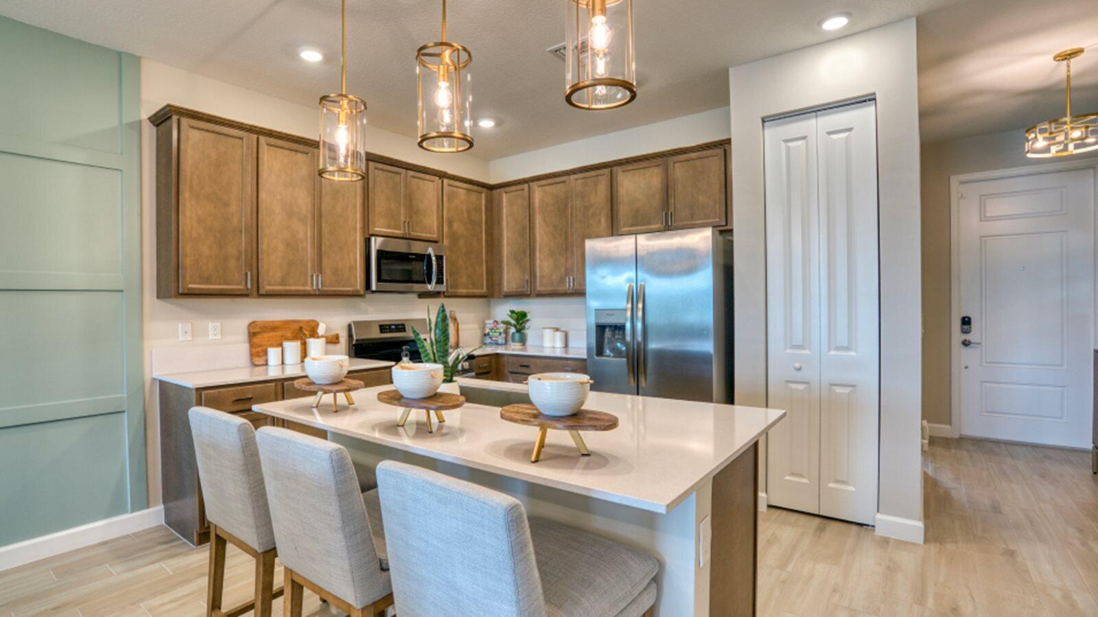 A kitchen features wood cabinets, stainless steel appliances, a quartz island, and three pendant lights — 13658 Jubilee Lane, Delray Beach FL 33484, DELRAY BEACH, FL