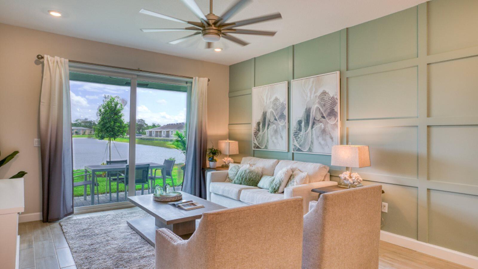 A living room features a green paneled wall, two armchairs, and sliding doors overlooking a lake — 13658 Jubilee Lane, Delray Beach FL 33484, DELRAY BEACH, FL
