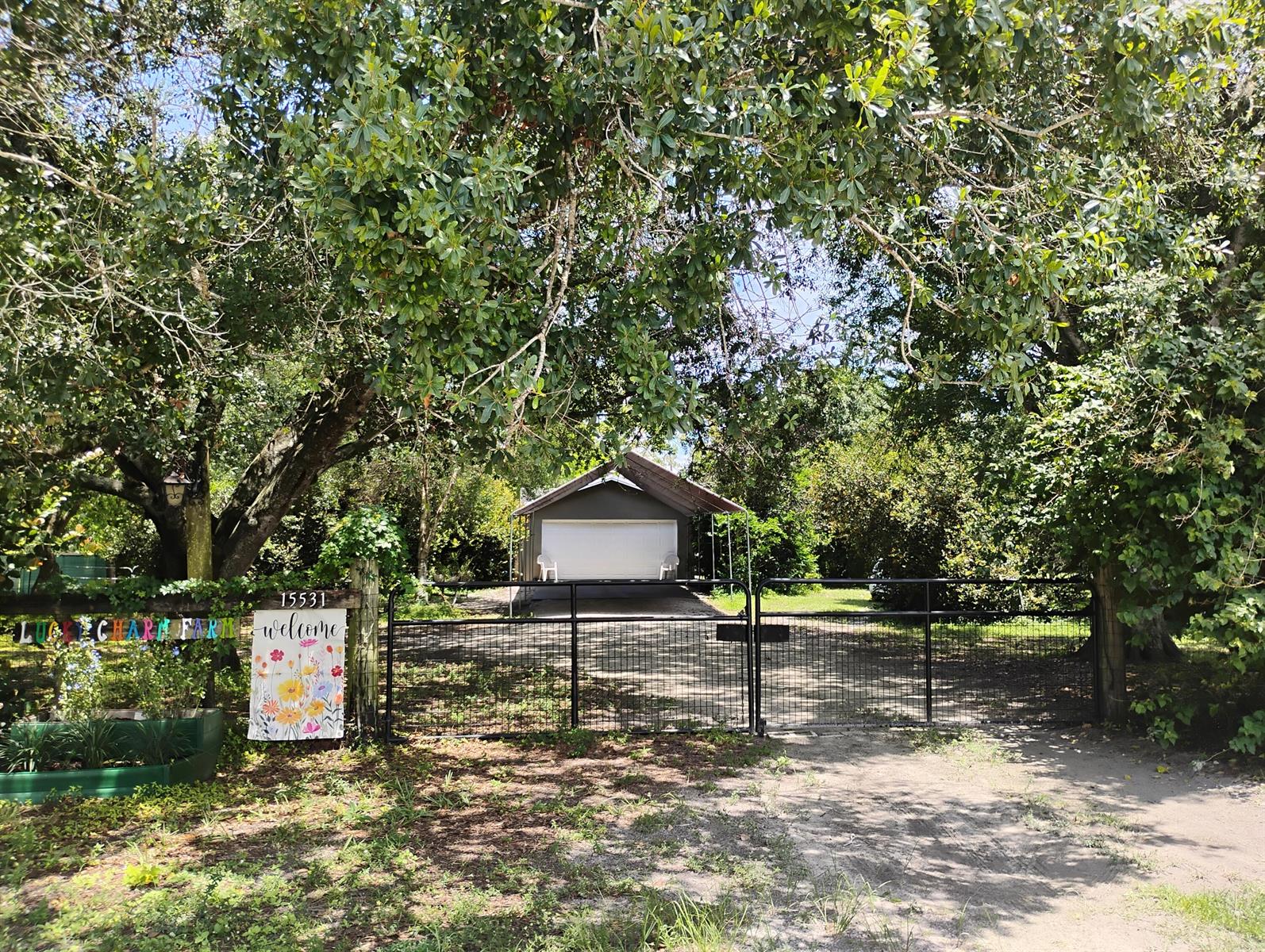 A gated driveway leads to a detached garage shaded by large trees on a rural property — 15531 42nd Road N, FL 33470, FL